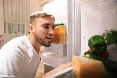 Photo of Young man choosing food in refrigerator, view from inside