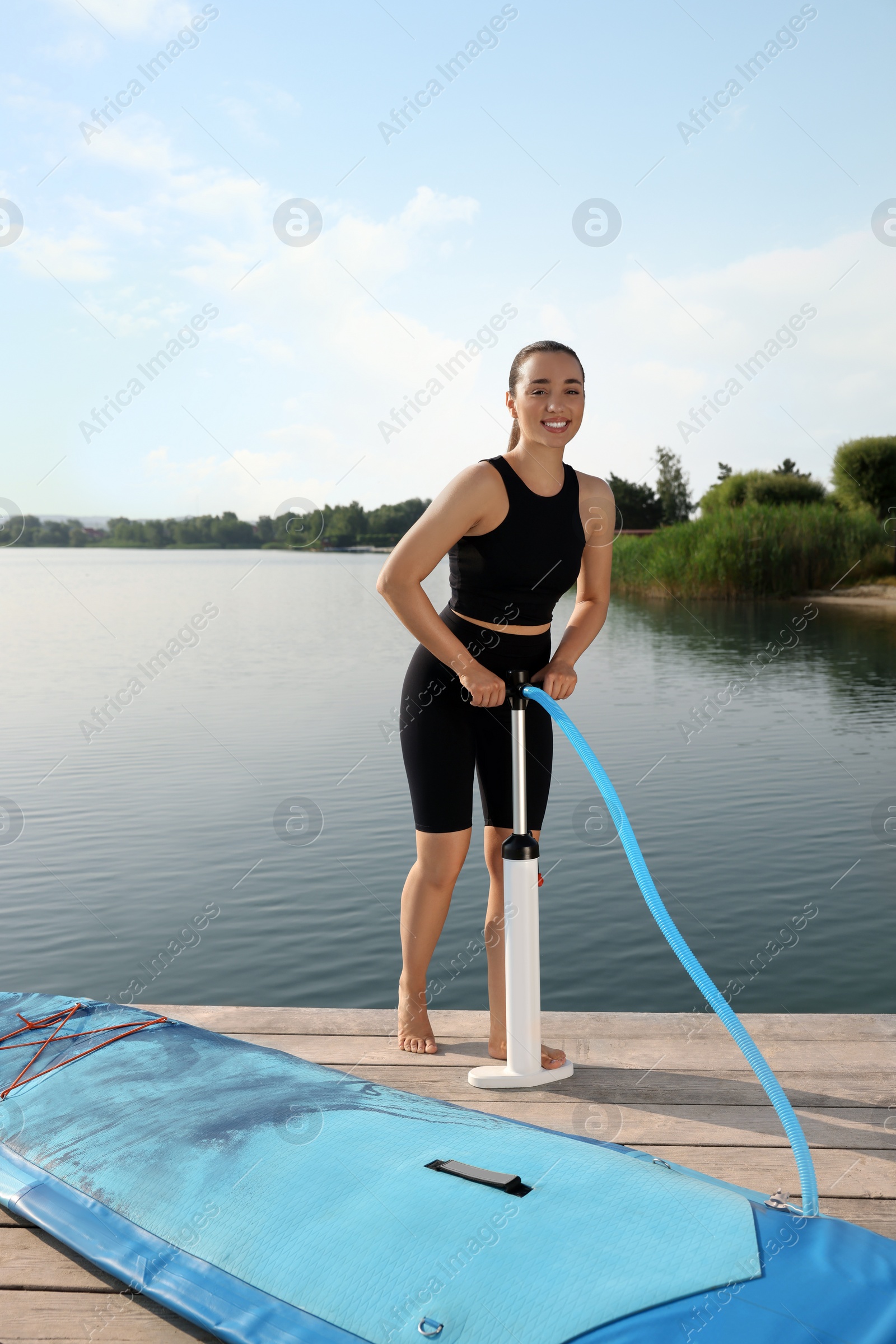 Photo of Woman pumping up SUP board on pier