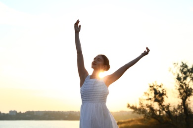 Photo of Beautiful woman enjoying nature near river. Zen and harmony