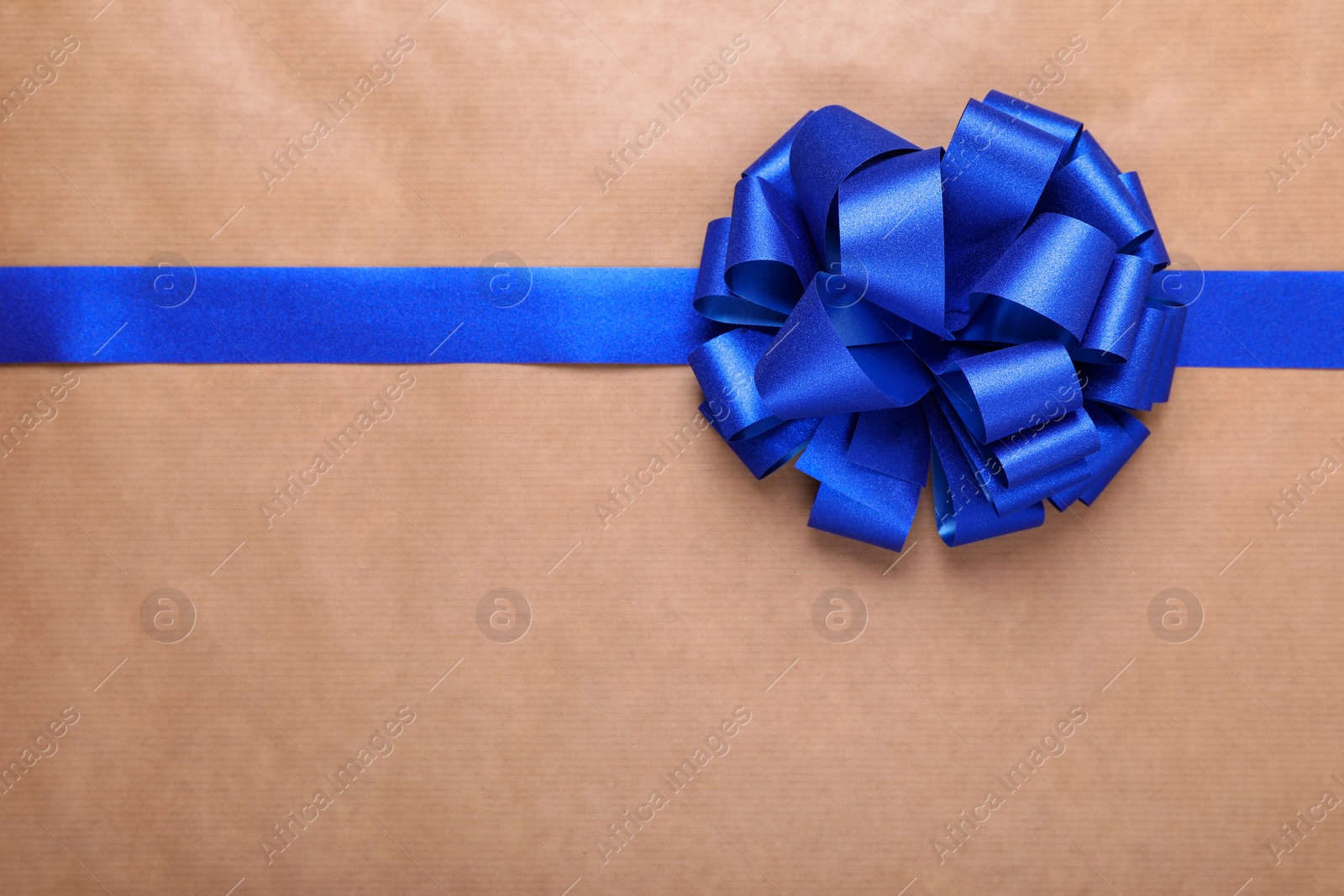 Photo of Blue ribbon with bow on beige background, top view. Space for text