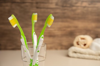 Toothbrushes in glass on blurred background, closeup. Space for text