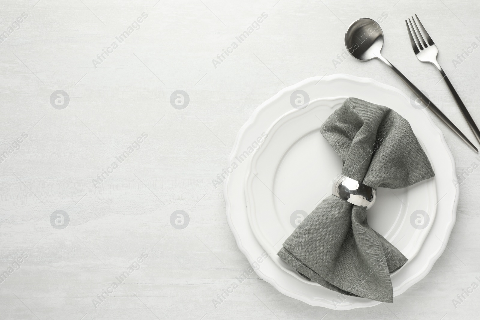 Photo of Stylish setting with cutlery, napkin and plates on light textured table, flat lay. Space for text