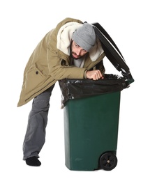 Poor homeless man digging in trash bin isolated on white