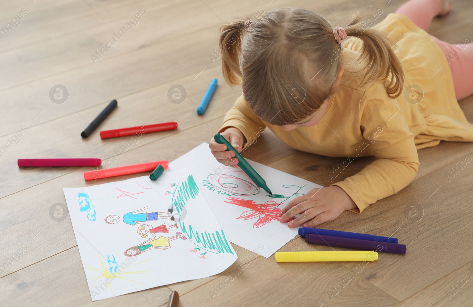 Photo of Cute little girl drawing with marker on floor. Child`s art