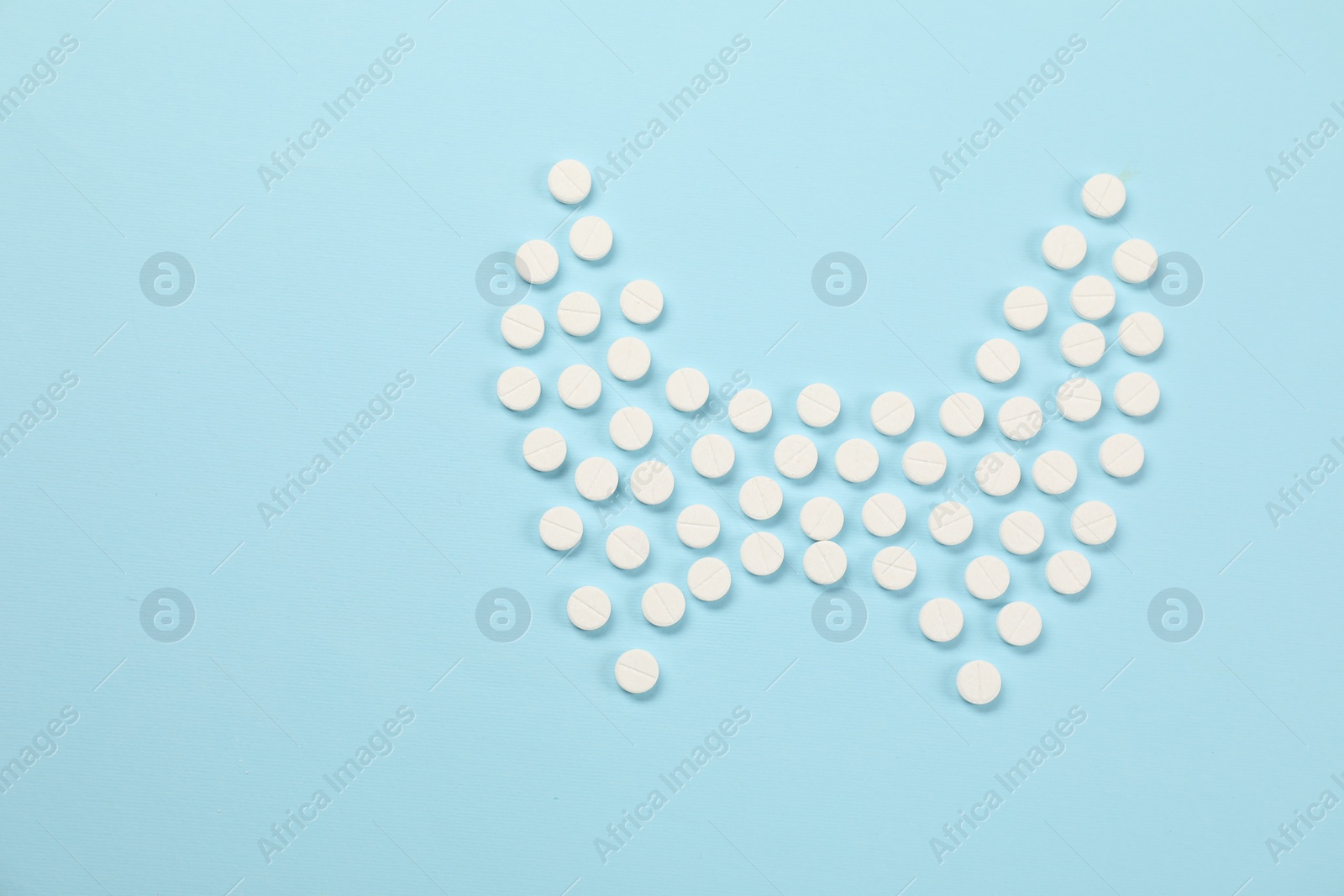 Photo of Endocrinology, Shape of thyroid gland made of pills on light blue background, flat lay. Space for text