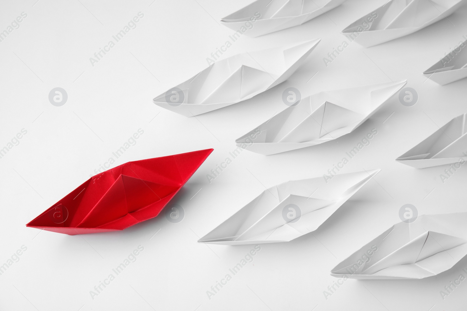 Photo of Group of paper boats following red one on white background, flat lay. Leadership concept