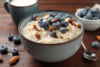 Photo of Tasty oatmeal porridge with blueberries and almond nuts on wooden table