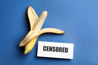 Photo of Card with word Censored and banana on blue background, flat lay