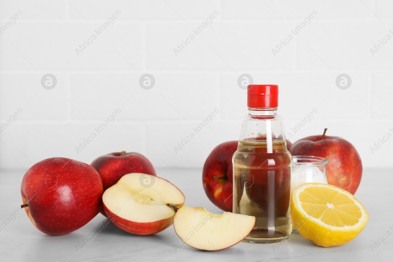 Photo of Apple vinegar, lemon and baking soda on white marble table. Eco friendly natural detergents