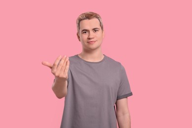 Photo of Happy man inviting to come in against pink background