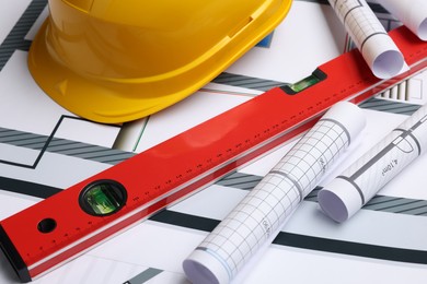 Construction drawings, safety hat and bubble level on house plan, closeup