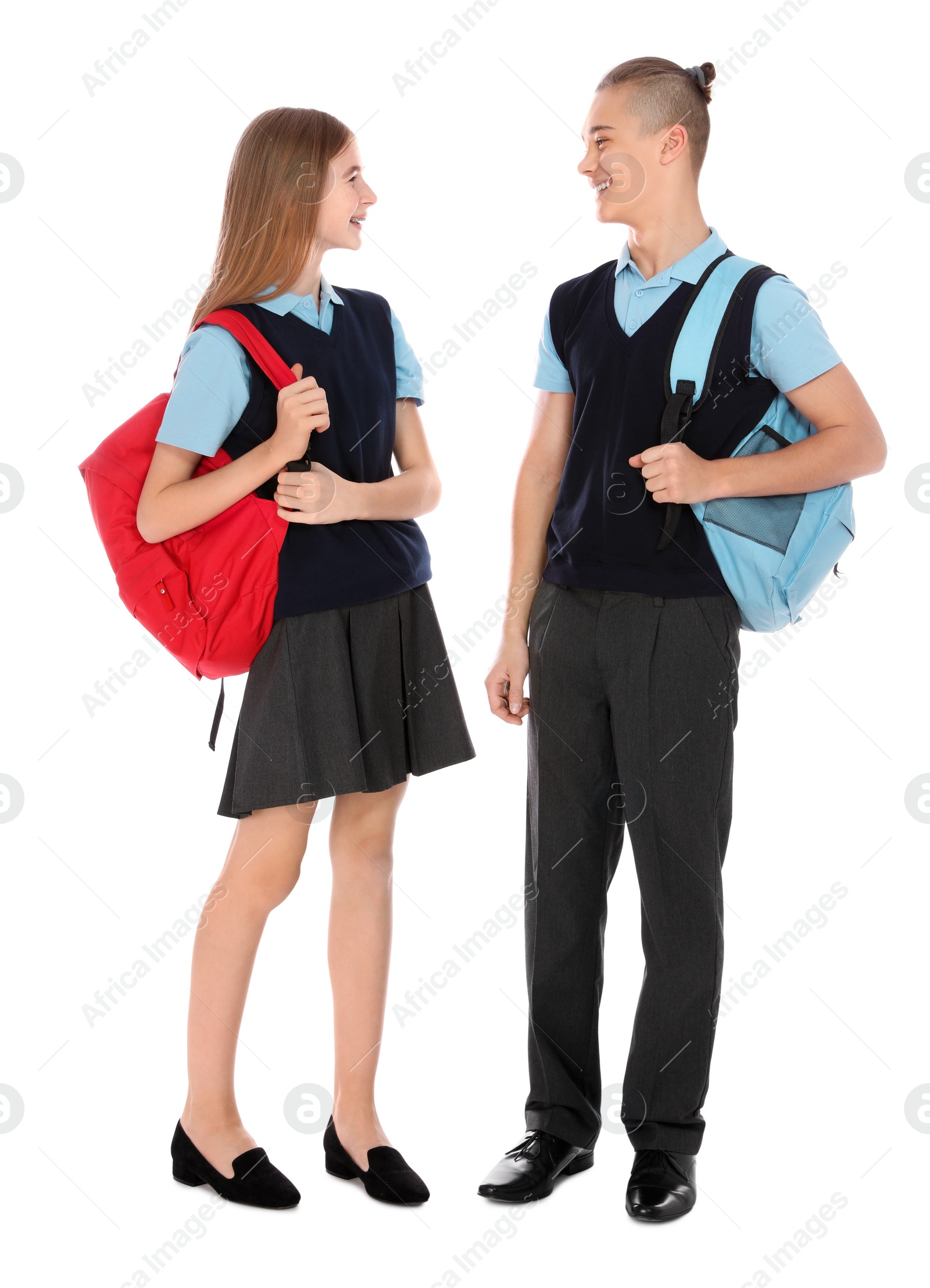 Photo of Full length portrait of teenagers in school uniform with backpacks on white background