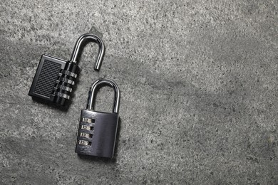 Photo of Steel combination padlocks on grey table, top view. Space for text