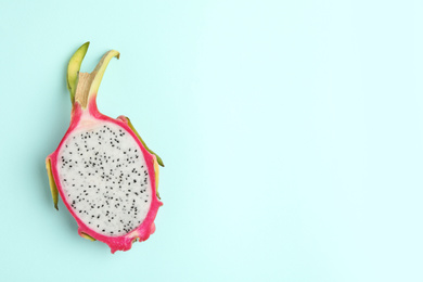 Photo of Half of delicious dragon fruit (pitahaya) on light blue background, top view. Space for text