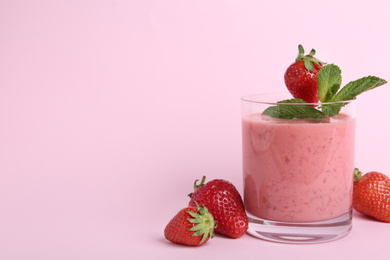 Photo of Tasty strawberry smoothie with mint in glass on pink background. Space for text