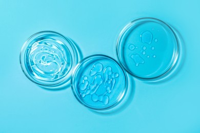 Photo of Petri dishes with liquids on light blue background, flat lay