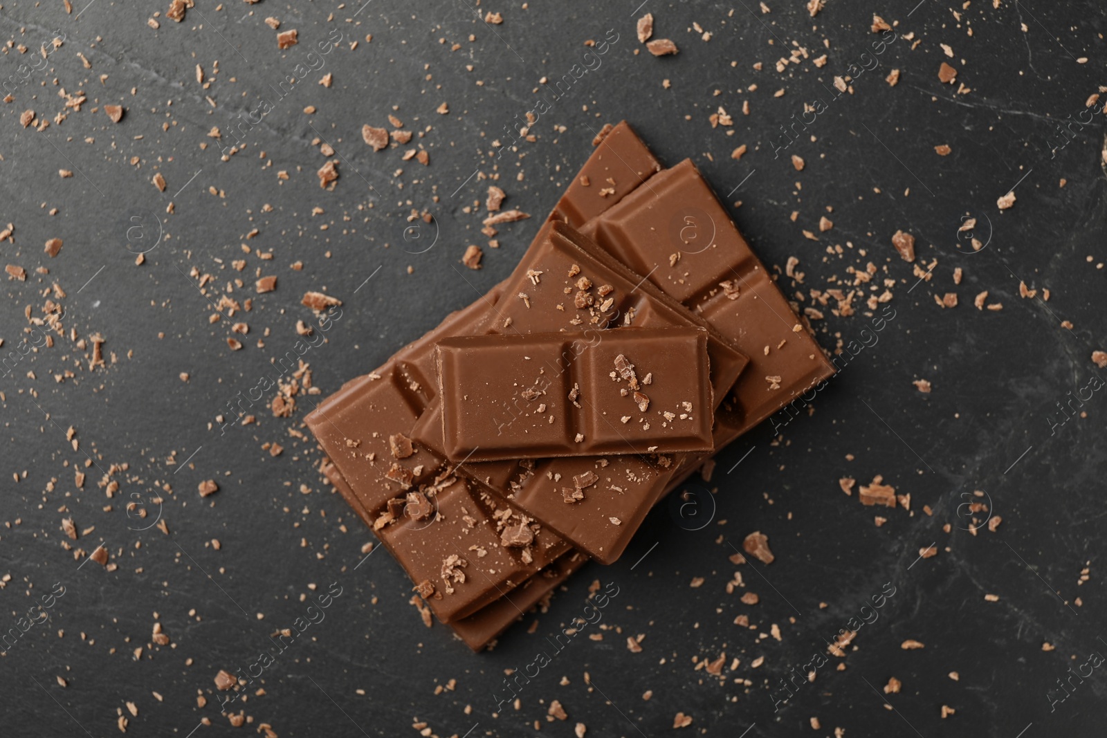 Photo of Pieces of tasty chocolate on grey table, top view