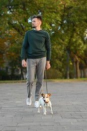 Photo of Man with adorable Jack Russell Terrier on city street. Dog walking