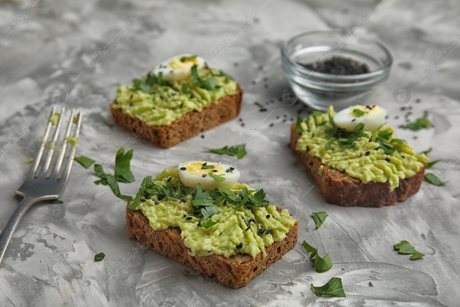 Photo of Crisp rye toasts with avocado and quail eggs on table
