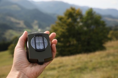 Photo of Woman using compass for navigation during journey in mountains, closeup