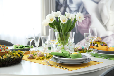 Photo of Festive Easter table setting with beautiful white tulips and eggs indoors