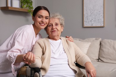 Photo of Portrait of young caregiver and senior woman indoors. Home care service