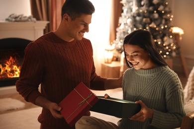 Photo of Couple opening gift box in living room with Christmas tree