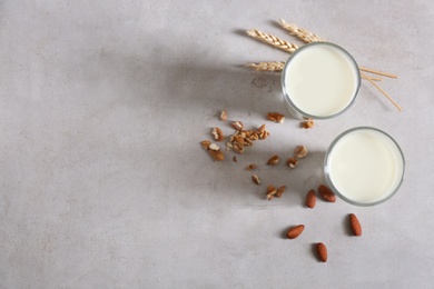 Glasses with milk and nuts on grey background, top view