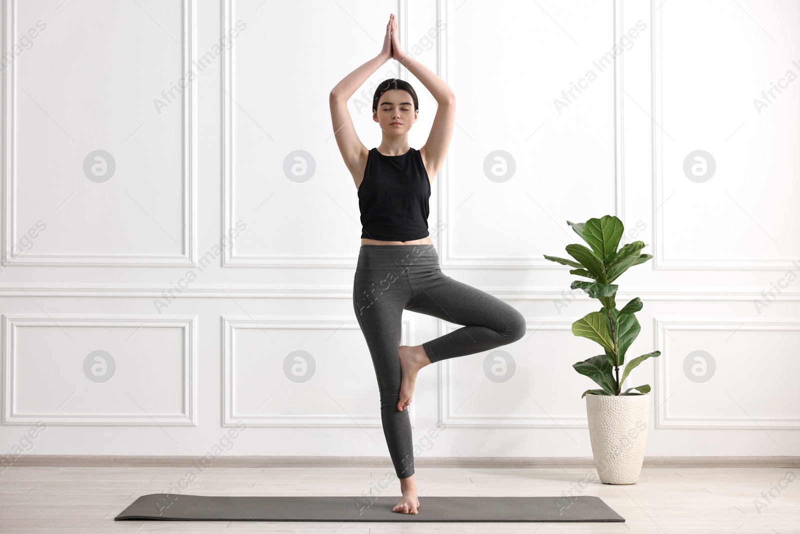 Photo of Girl practicing tree asana on mat in yoga studio. Vrksasana pose