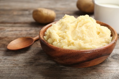 Photo of Bowl with mashed potatoes on wooden table