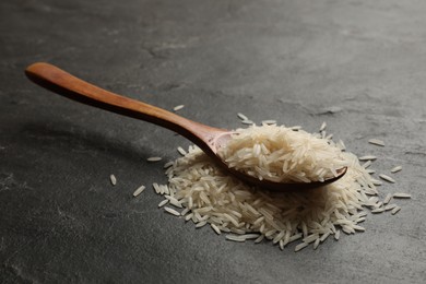 Photo of Raw basmati rice and wooden spoon on black table