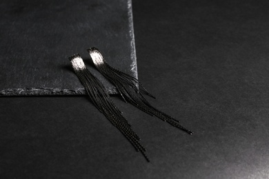 Photo of Elegant earrings on black background, space for text. Luxury jewelry