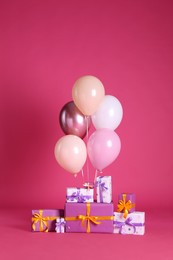 Many gift boxes and balloons near bright pink background