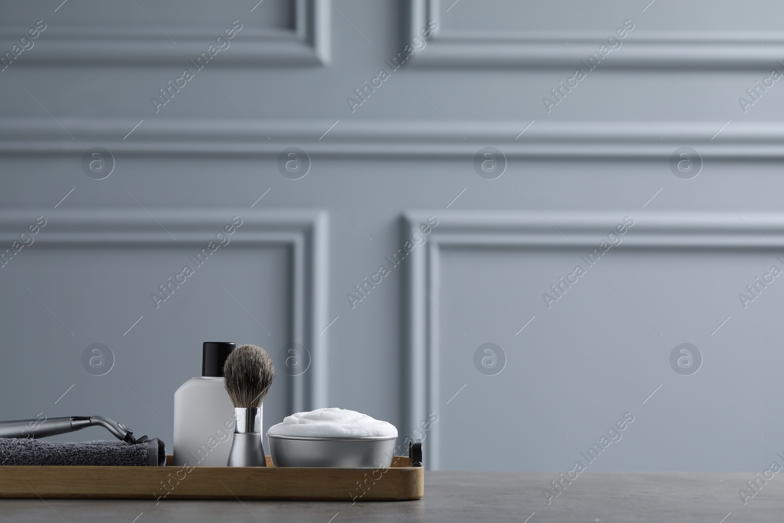 Photo of Set of men's shaving tools in wooden tray on grey table. Space for text