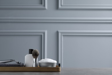 Photo of Set of men's shaving tools in wooden tray on grey table. Space for text