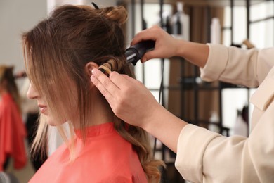 Stylist working with client in salon, making hairstyle