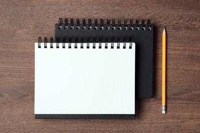 Stylish notebooks and pencil on wooden table, flat lay