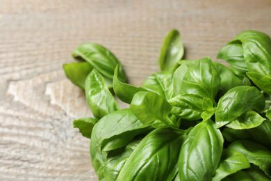 Fresh basil leaves on wooden table, closeup