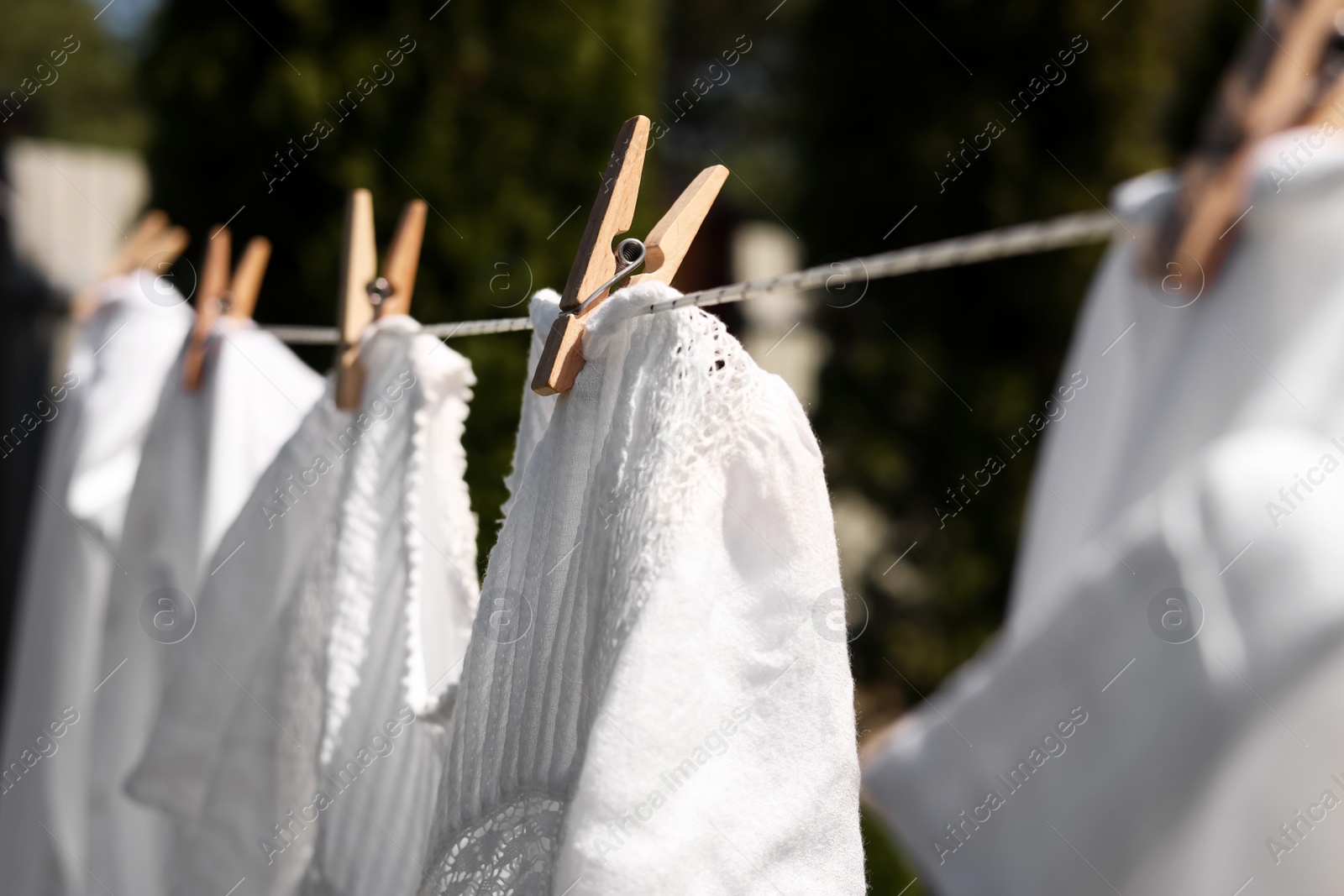 Photo of Clean clothes hanging on washing line in garden, closeup. Drying laundry