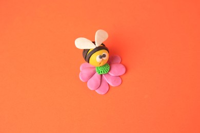 Bee with flower made from plasticine on orange background. Children's handmade ideas