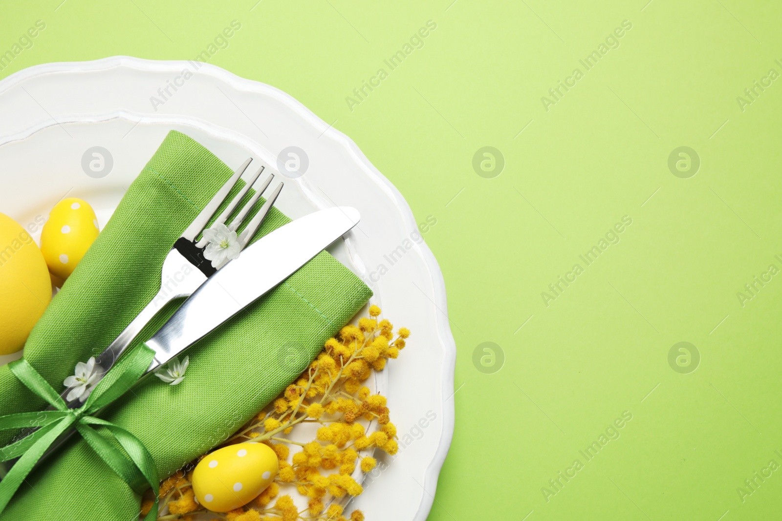 Photo of Festive Easter table setting with floral decor on green background, top view. Space for text