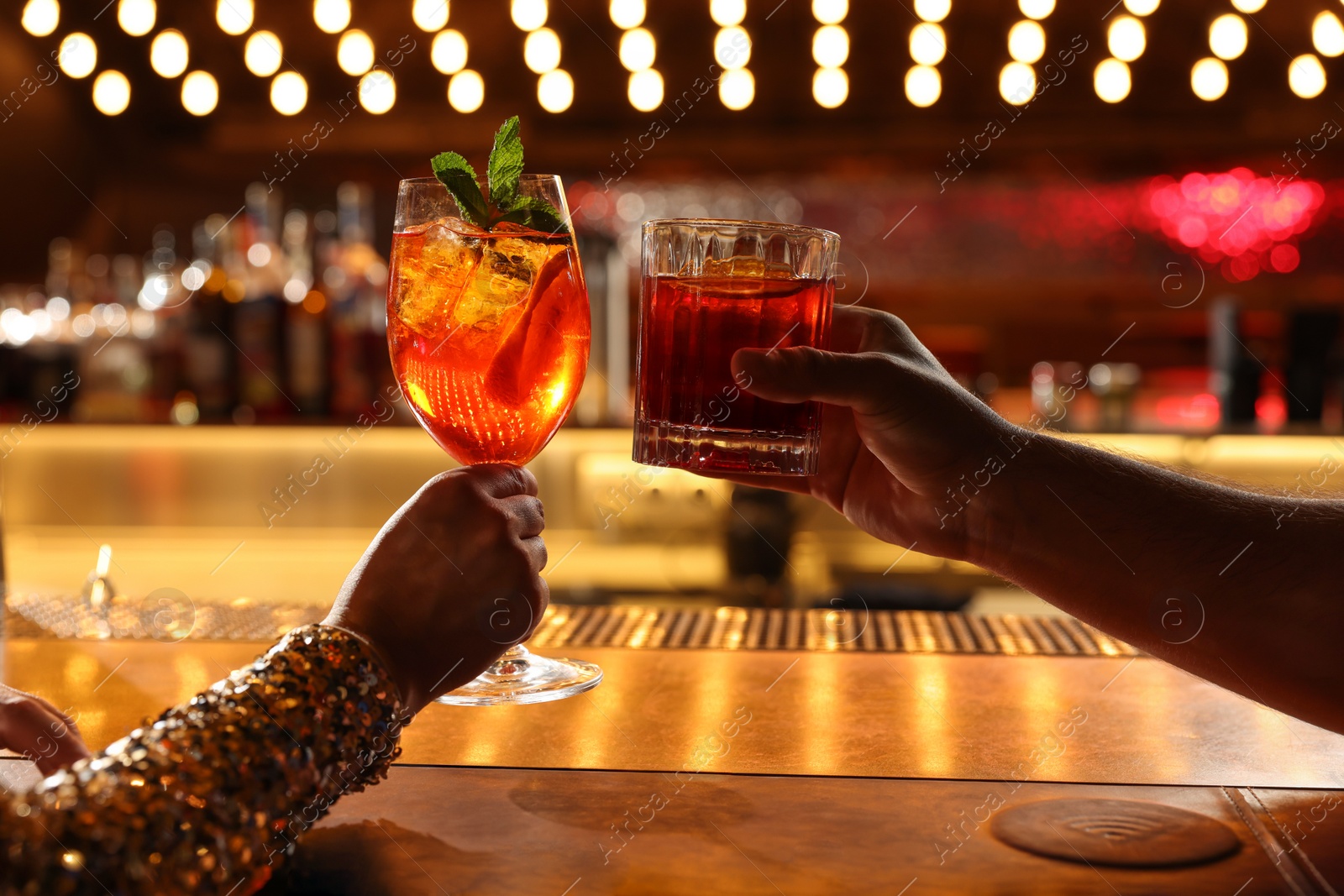 Photo of People holding glasses with fresh cocktails at bar counter, closeup