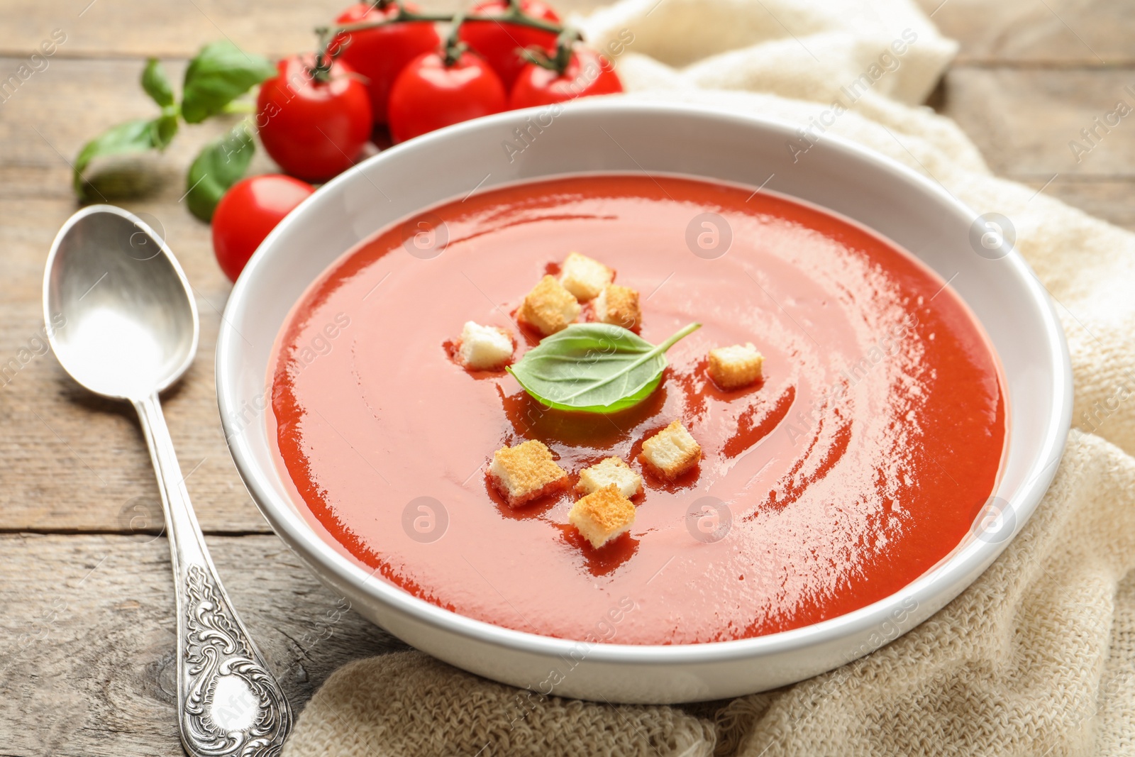 Photo of Bowl with fresh homemade tomato soup on wooden table