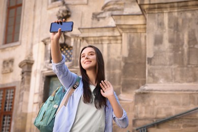 Photo of Beautiful travel blogger with smartphone streaming outdoors