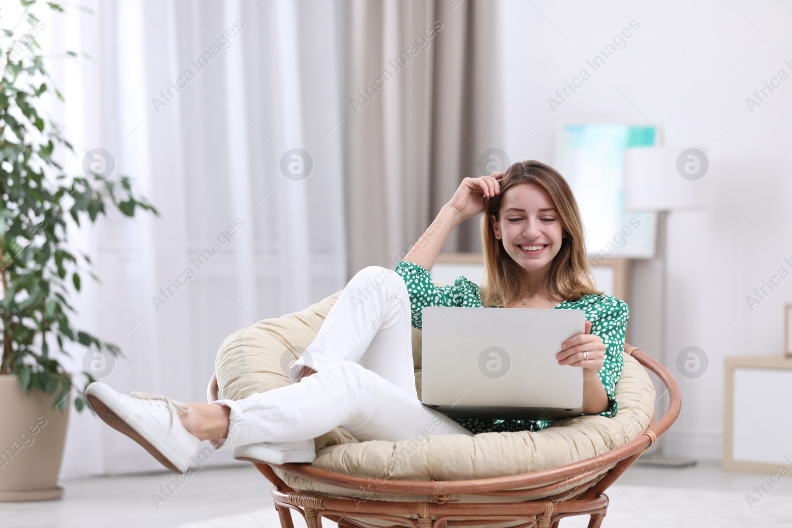 Photo of Attractive young woman with laptop in armchair at home