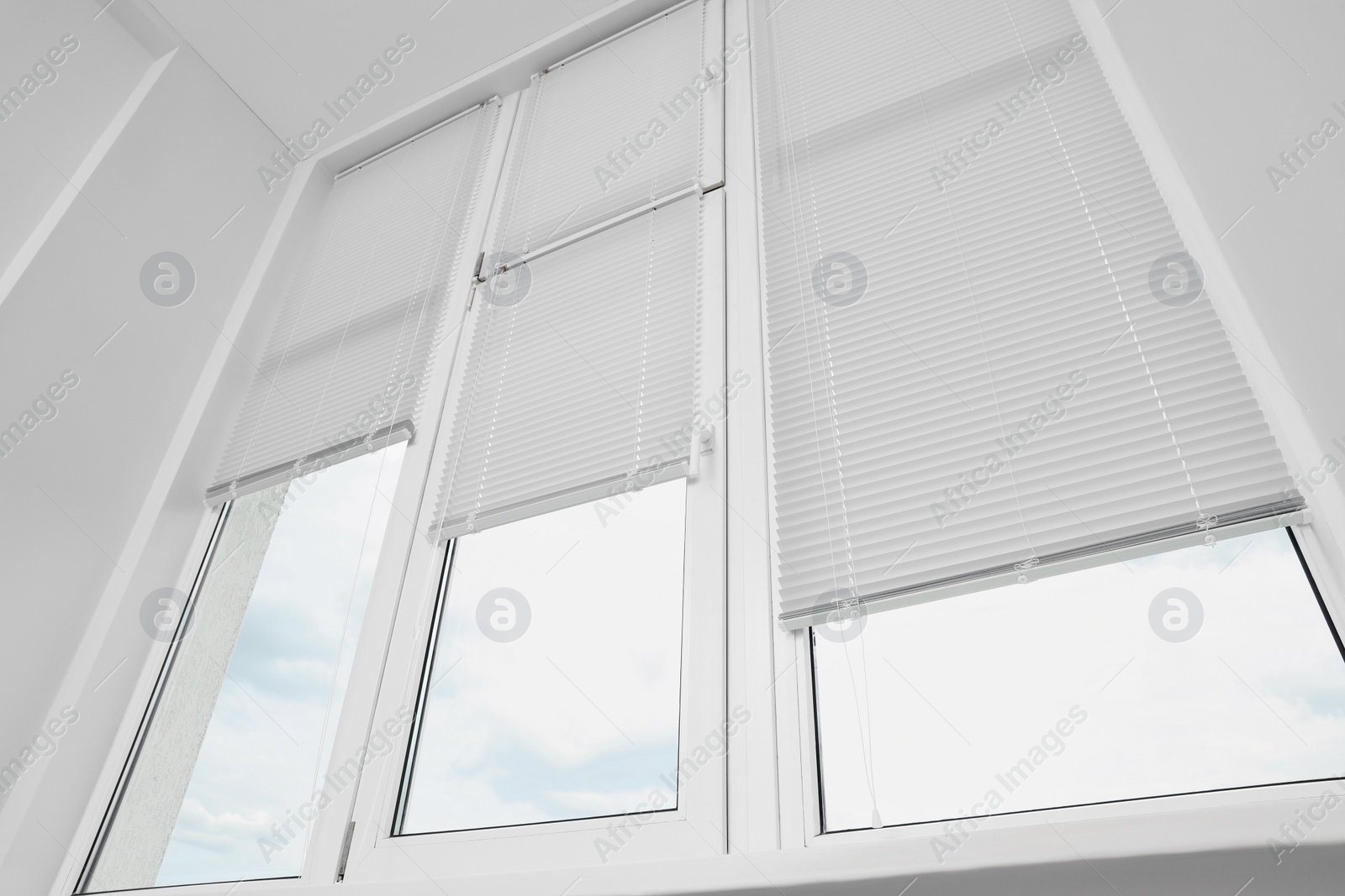 Photo of Stylish window with horizontal blinds in room, low angle view