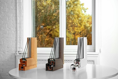 Photo of Samples of modern window profiles on table indoors. Installation service