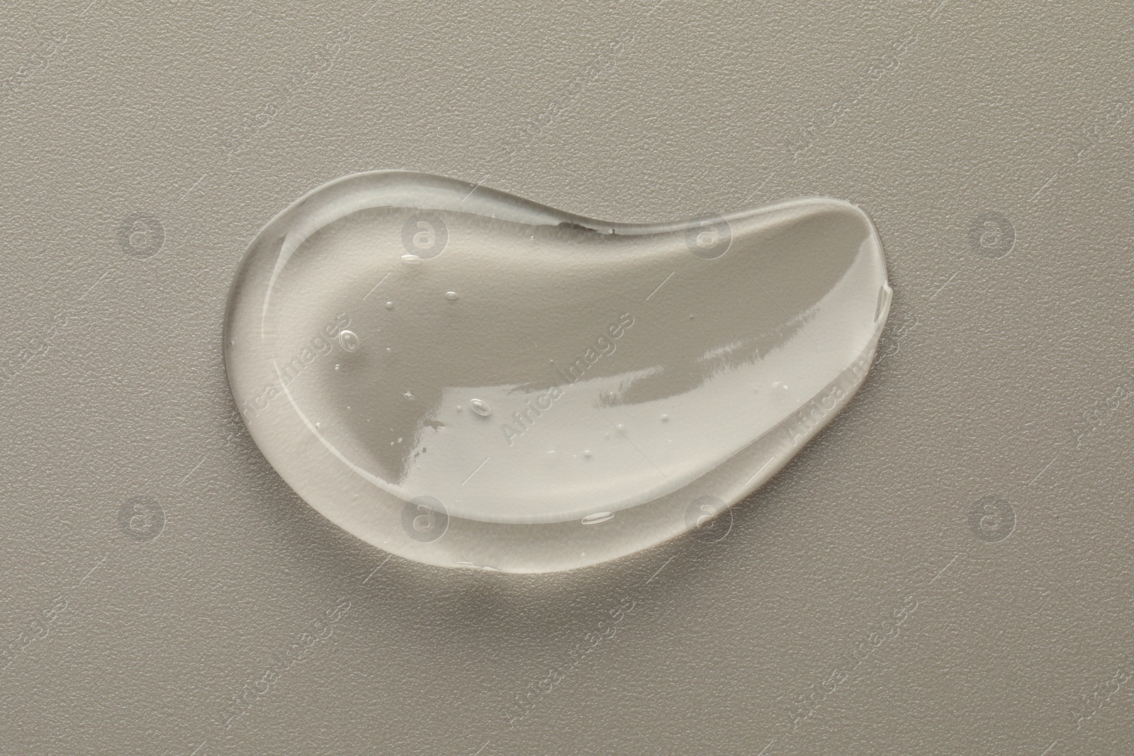 Photo of Smear of clear cosmetic gel on grey background, top view