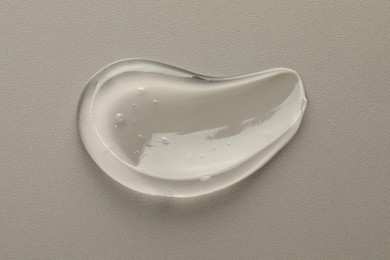 Smear of clear cosmetic gel on grey background, top view