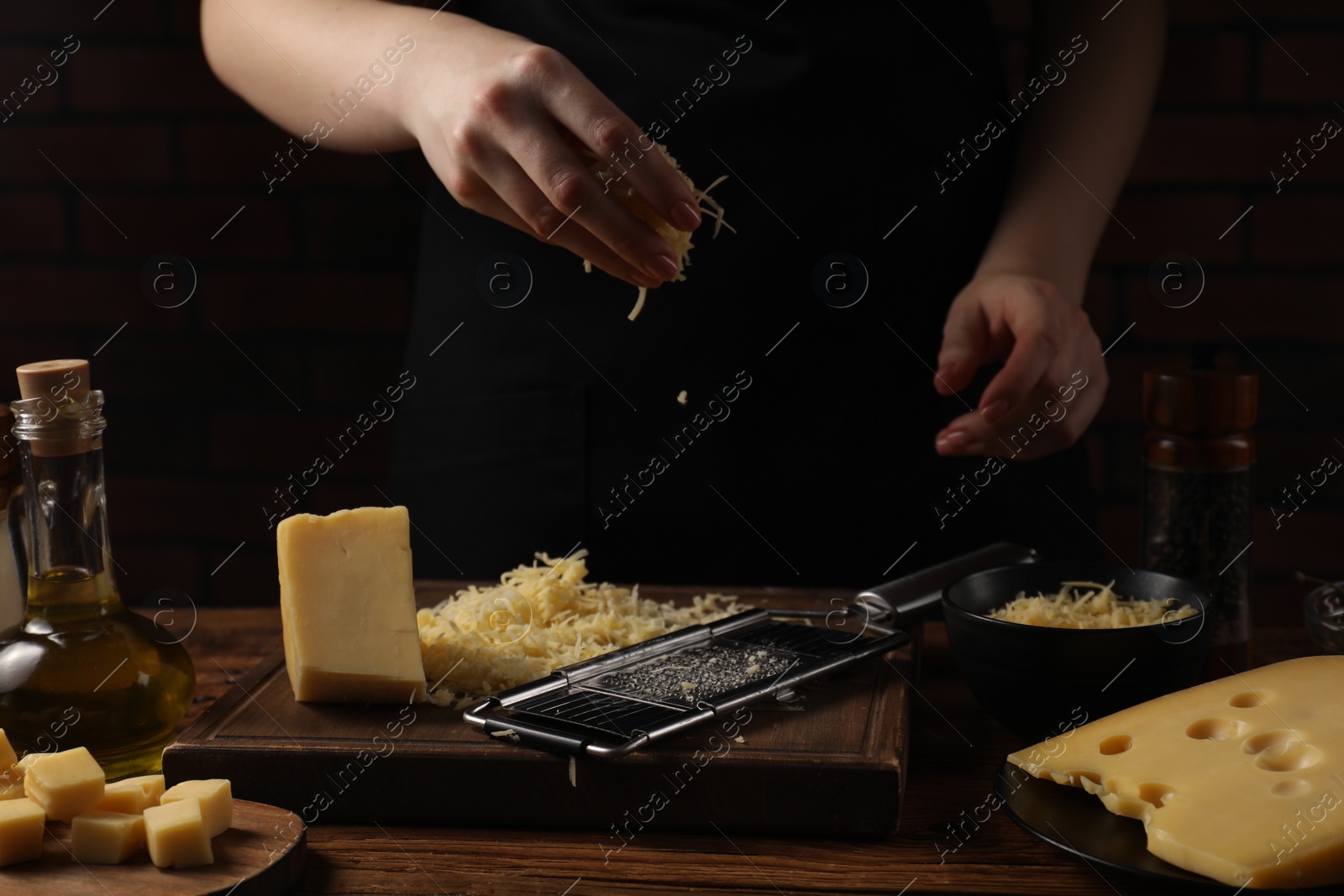 Photo of Woman with grated cheese at wooden table, closeup